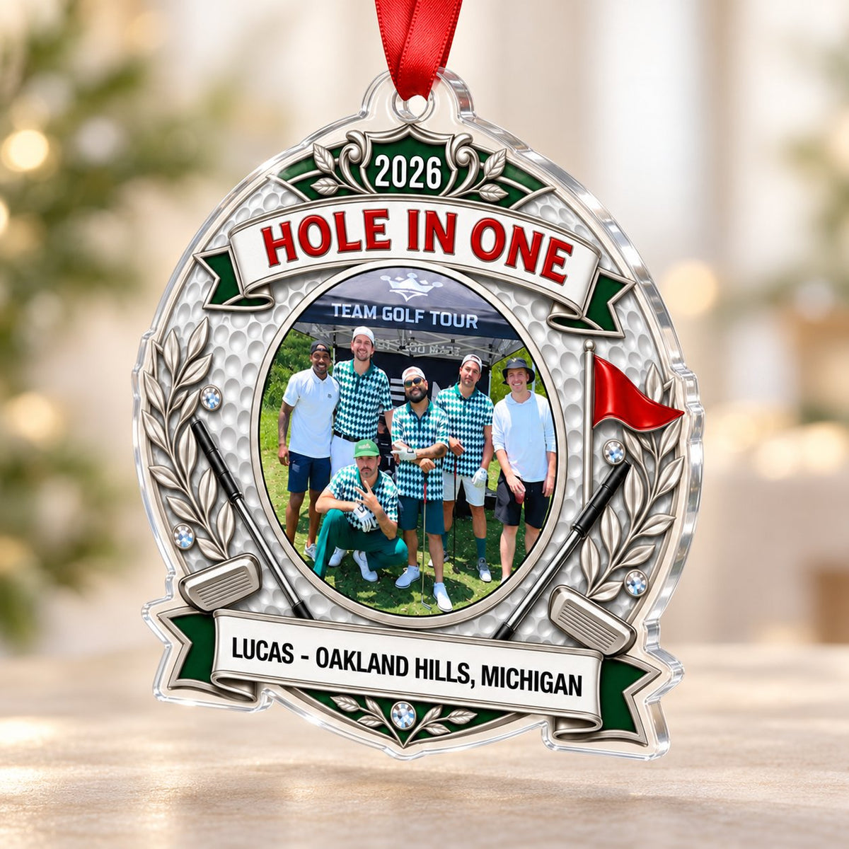 Silver trophy-style golf ornament with laurel branches, crossed clubs, red flag, 2026 and HOLE IN ONE, plus a circular p
