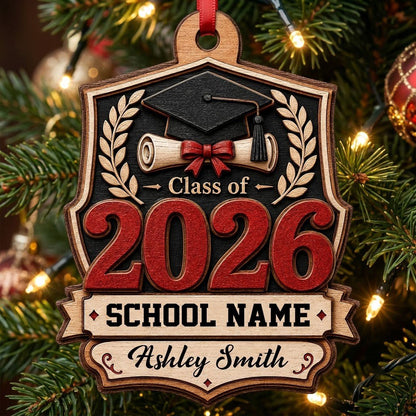 Shield-shaped wood ornament with Class of 2026, cap, diploma, laurel branches, and a personalized name and school