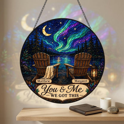 Round stained-glass style suncatcher with aurora, crescent moon, pine trees, lake, two chairs and a lantern.