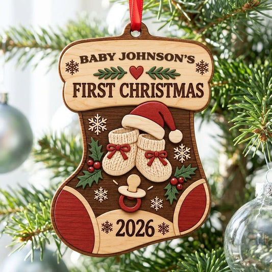 Stocking-shaped wood ornament with baby booties, Santa hat, holly, snowflakes, and FIRST CHRISTMAS text.