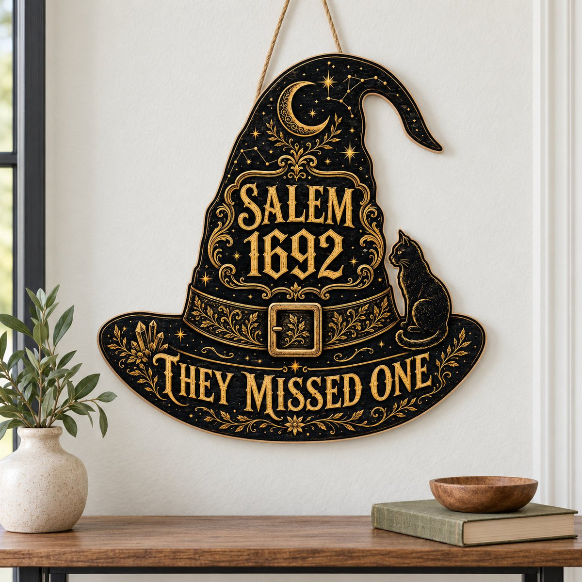 Witch hat-shaped wooden sign with 'SALEM 1692 THEY MISSED ONE', crescent moon, stars, filigree, and a black cat on the b