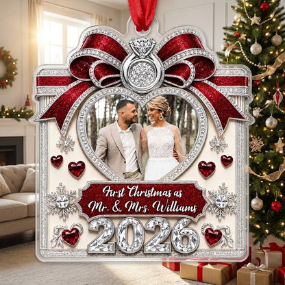 Acrylic ornament with red glitter bow, engagement ring, heart photo frame, snowflakes, and Mr. & Mrs. name and year.