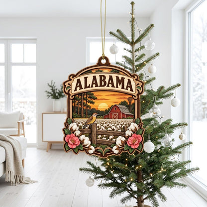 Custom-cut wood ornament with “ALABAMA”, red barn, windmill, yellowhammer bird, cotton and pink camellias at sunset.