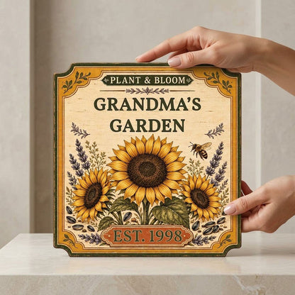 Square bracketed wooden sign with three sunflowers, lavender, a honeybee, and “Plant & Bloom” and “Grandma’s Garden” tex