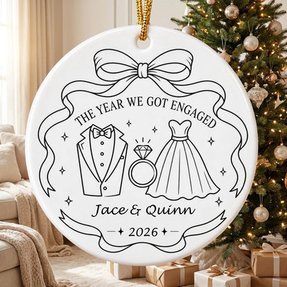 Round white ceramic ornament with black line art of bow, tuxedo, ring, dress, and THE YEAR WE GOT ENGAGED banner.