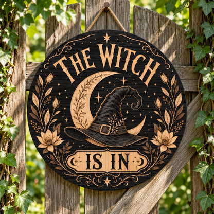 Round wooden sign with 'THE WITCH IS IN' slogan, crescent moon, witch hat, floral borders, stars and scrollwork.