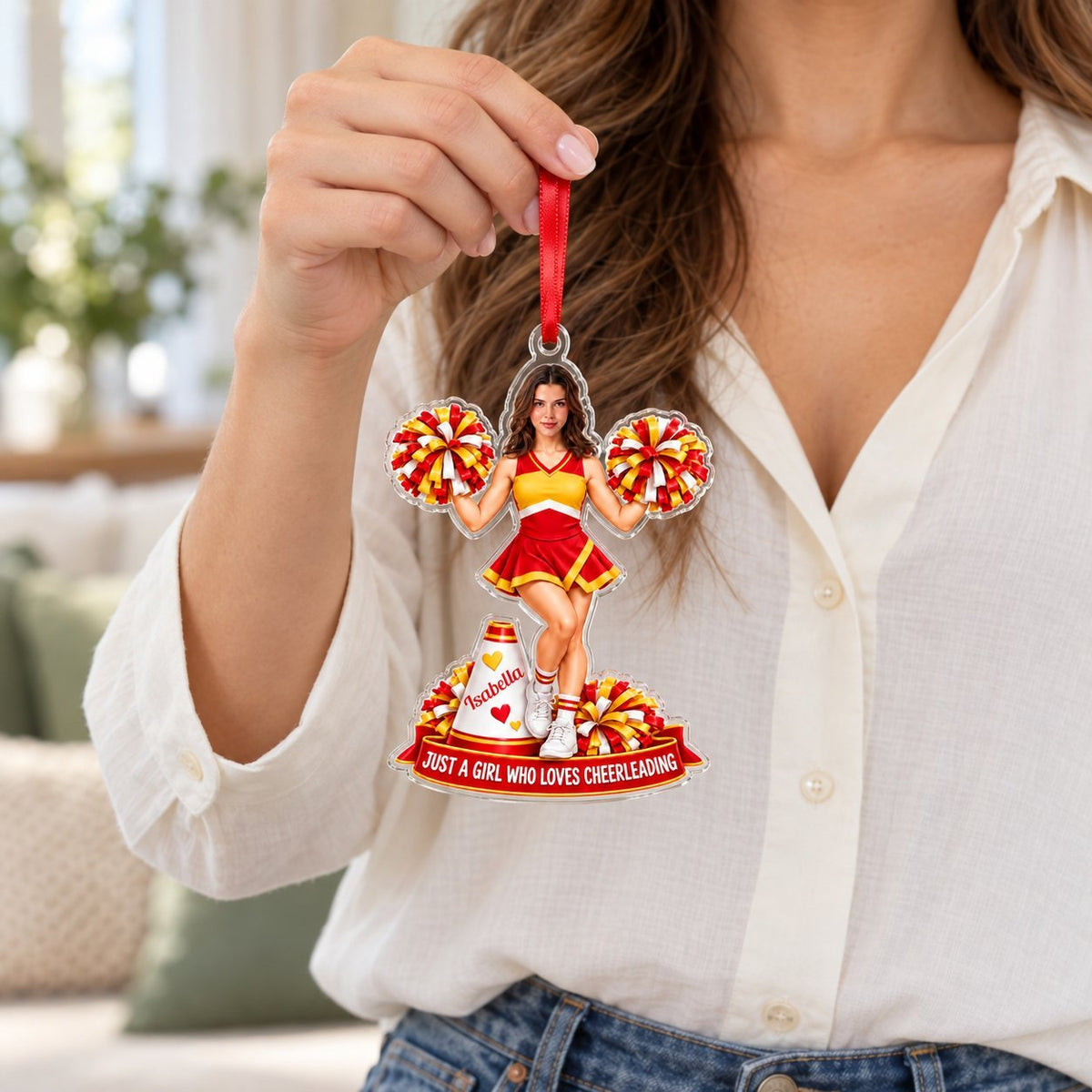 Custom-cut acrylic ornament of a cheerleader in red and yellow with pom-poms, a white megaphone, and a red name banner