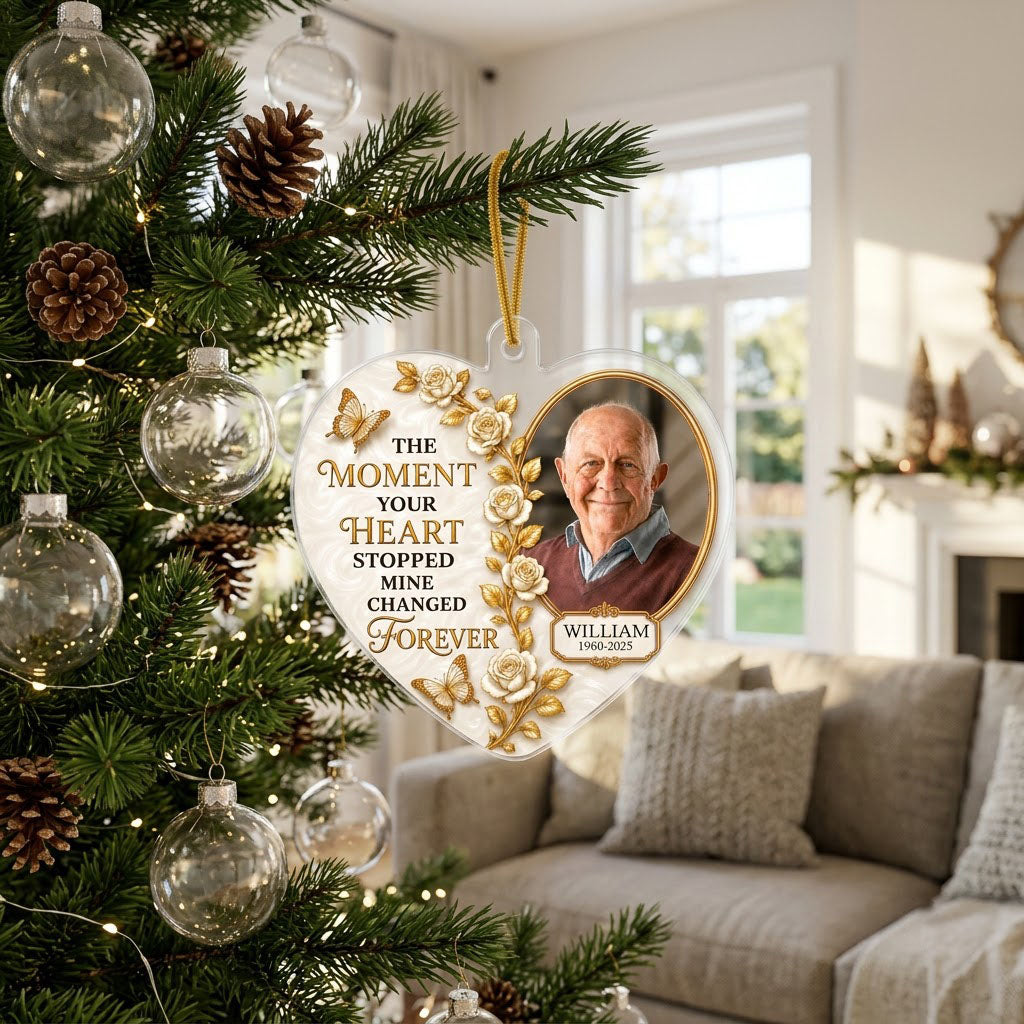 Heart-shaped acrylic ornament with a photo in a gold oval frame, white roses, gold butterflies, and a name plaque.