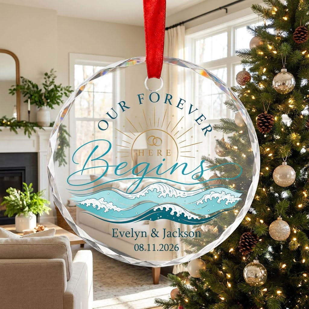 Round glass ornament with gold sun, interlocking rings, teal ocean waves, and 'OUR FOREVER HERE Begins' text.