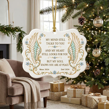 Medallion ceramic ornament with gold-outlined angel wings, blue forget-me-nots, and a memorial quote with name and year.