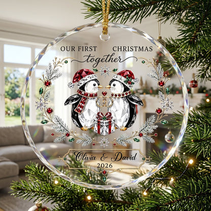 Penguin couple in Santa hats hold gold rings beneath a heart, framed by a pine and gem wreath with a gift box.