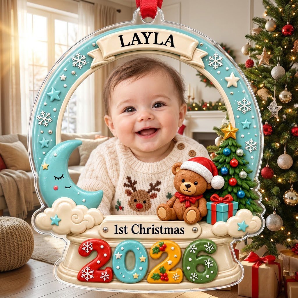 Acrylic snow-globe ornament with baby photo, "1st Christmas", teddy bear, moon, clouds, and big 2026 at the base.