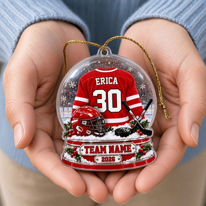 Acrylic snow globe ornament with red hockey jersey, helmet, crossed sticks, puck, holly and a silver name plaque.