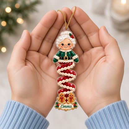 Clear acrylic ornament with a cartoon elf or Mrs. Claus, spiral ribbon body, holly, and a white name scroll.
