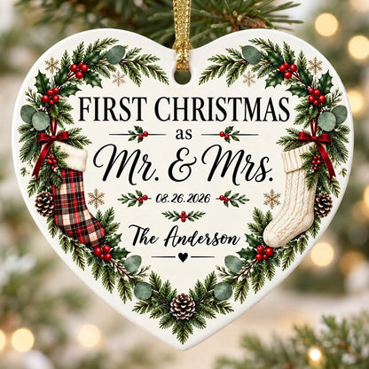 Heart ornament with greenery border, two stockings on bows, and 'FIRST CHRISTMAS as Mr. & Mrs.' text.