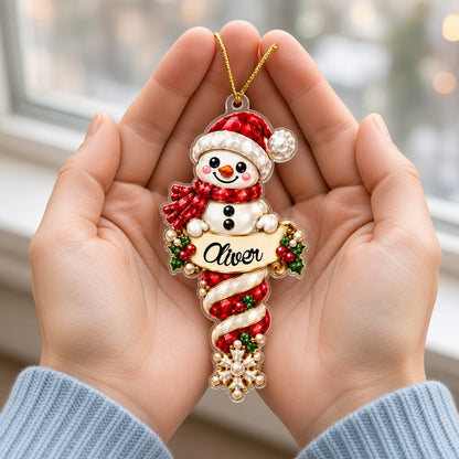 Custom-cut acrylic snowman ornaments with red scarves and scroll banners personalized with a child's name.