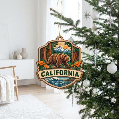 Shield-shaped wood ornament reading CALIFORNIA with bear on log, poppies, redwoods, mountains, and ocean waves.