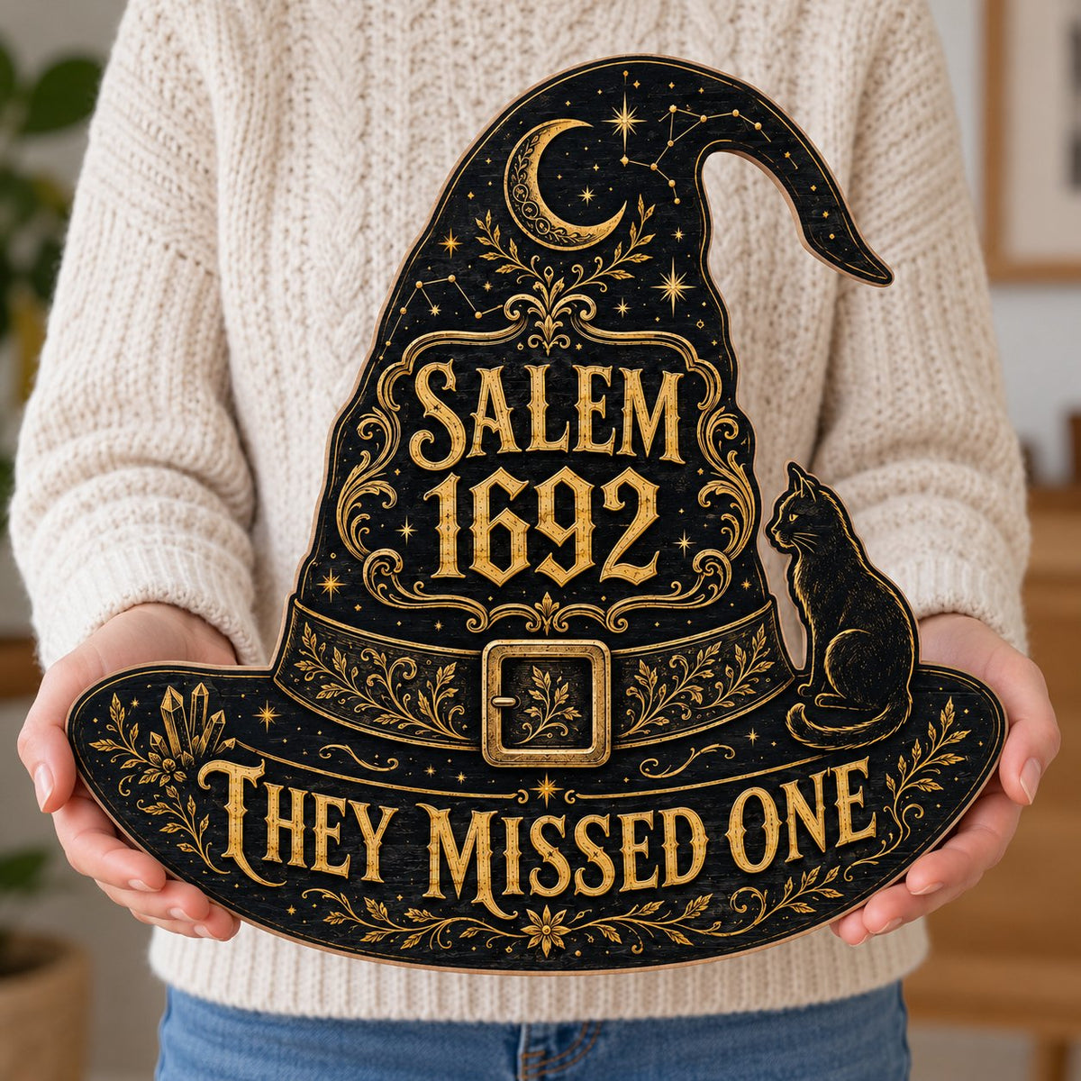 Witch hat-shaped wooden sign with 'SALEM 1692 THEY MISSED ONE', crescent moon, stars, filigree, and a black cat on the b