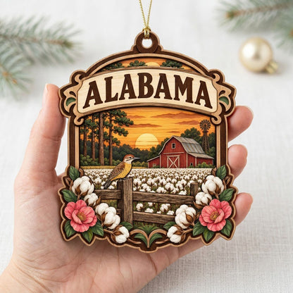 Custom-cut wood ornament with “ALABAMA”, red barn, windmill, yellowhammer bird, cotton and pink camellias at sunset.