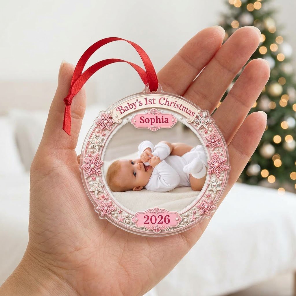 Round acrylic ornament with pink and white snowflakes framing a baby photo and the words Baby's 1st Christmas.