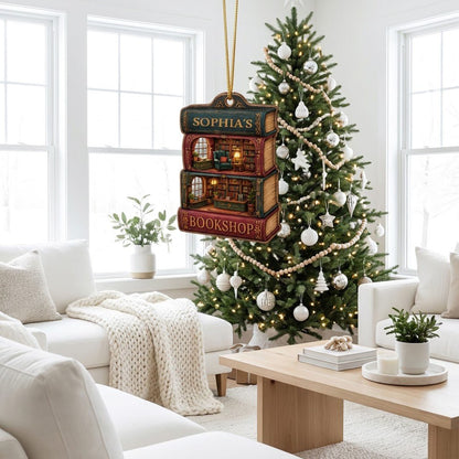 Custom-cut ornament of stacked books showing cozy bookshop rooms, BOOKSHOP text, and a personalized name.