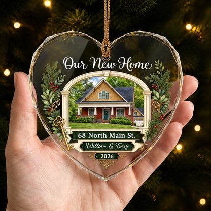 Heart glass ornament with archway, brick and yellow house, pine branches, gold key, and 'Our New Home' text.