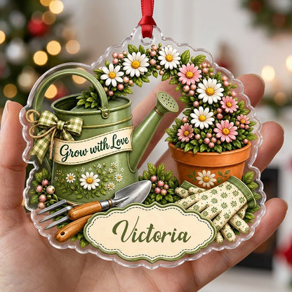 Green watering can with bow, garden tools, and floral pot with ‘Grow with Love’ and a name on a clear acrylic ornament.