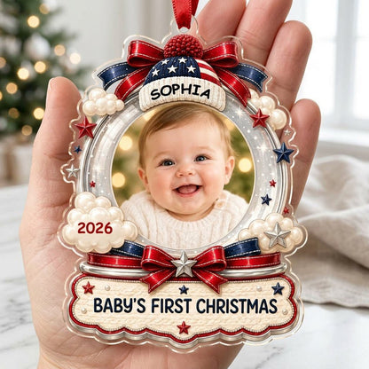 Custom-cut acrylic ornament with baby's photo, patriotic beanie, red bows, stars, and 'Baby's First Christmas' banner.