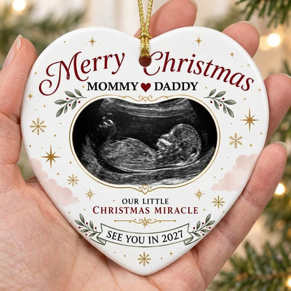 Heart ceramic ornament with ultrasound photo, gold starbursts, green leaves with red berries, and a bottom banner.