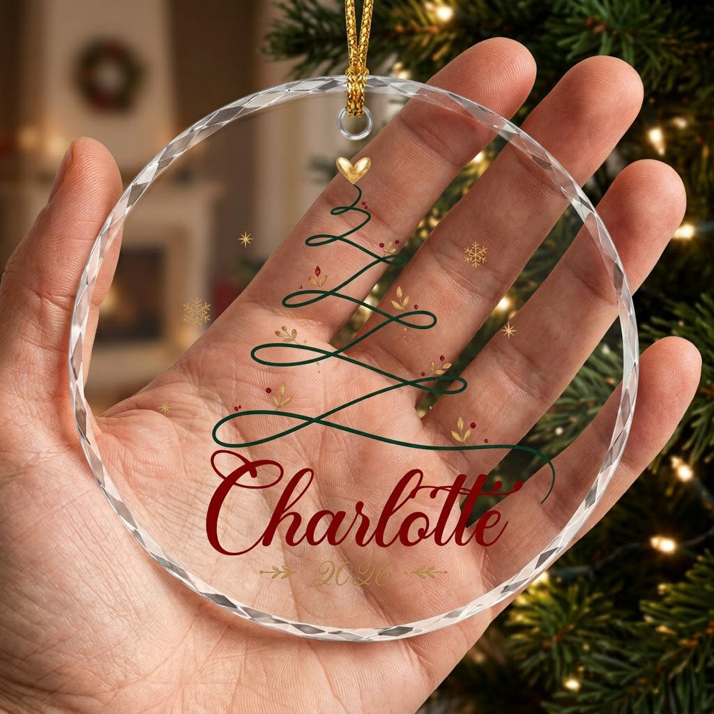 Clear round glass ornament with a looping green line Christmas tree topped by a small gold heart, name and year.