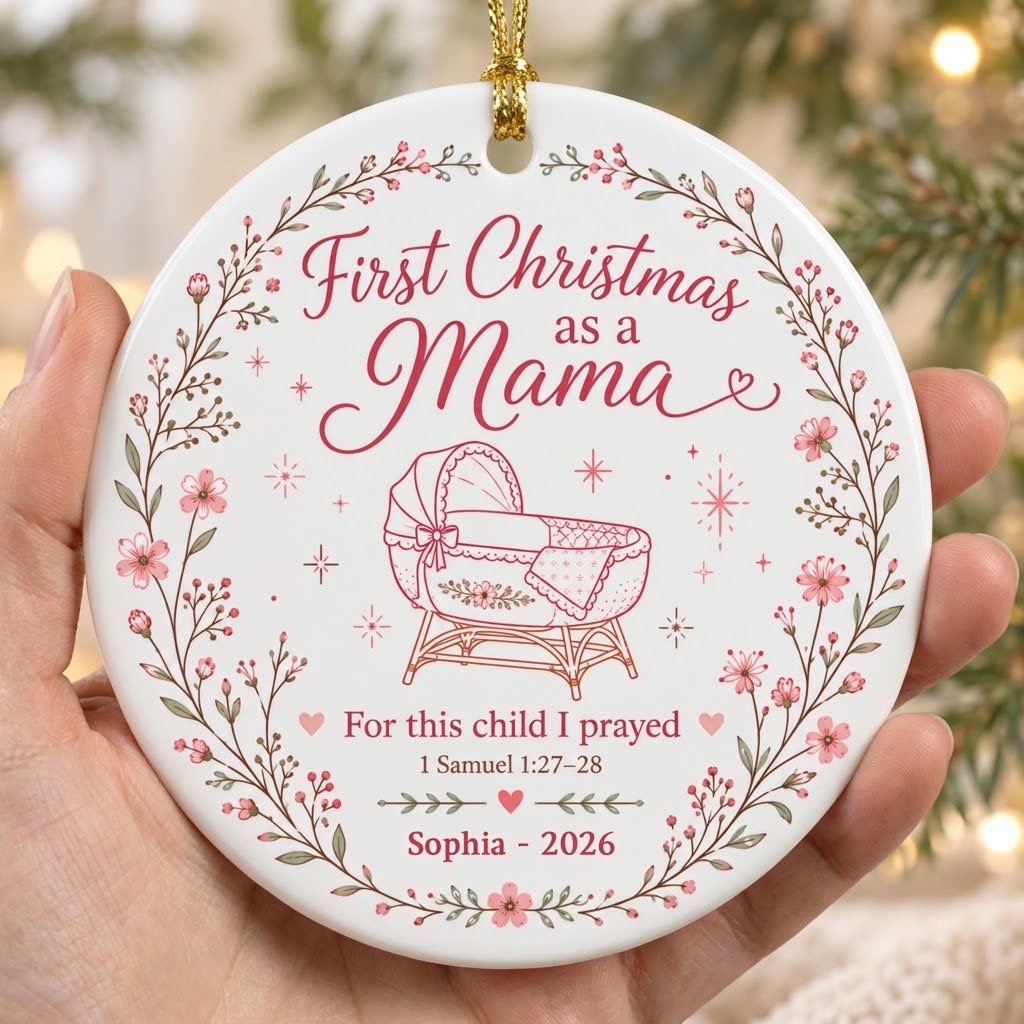 Round ceramic ornament with pink floral wreath, baby bassinet line art, stars, and First Christmas as a Mama.