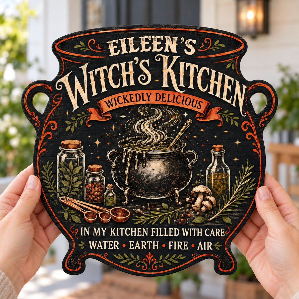 Custom-cut wooden sign shaped like a cauldron with herbs, potion jars, orange scroll and Witch's Kitchen text.