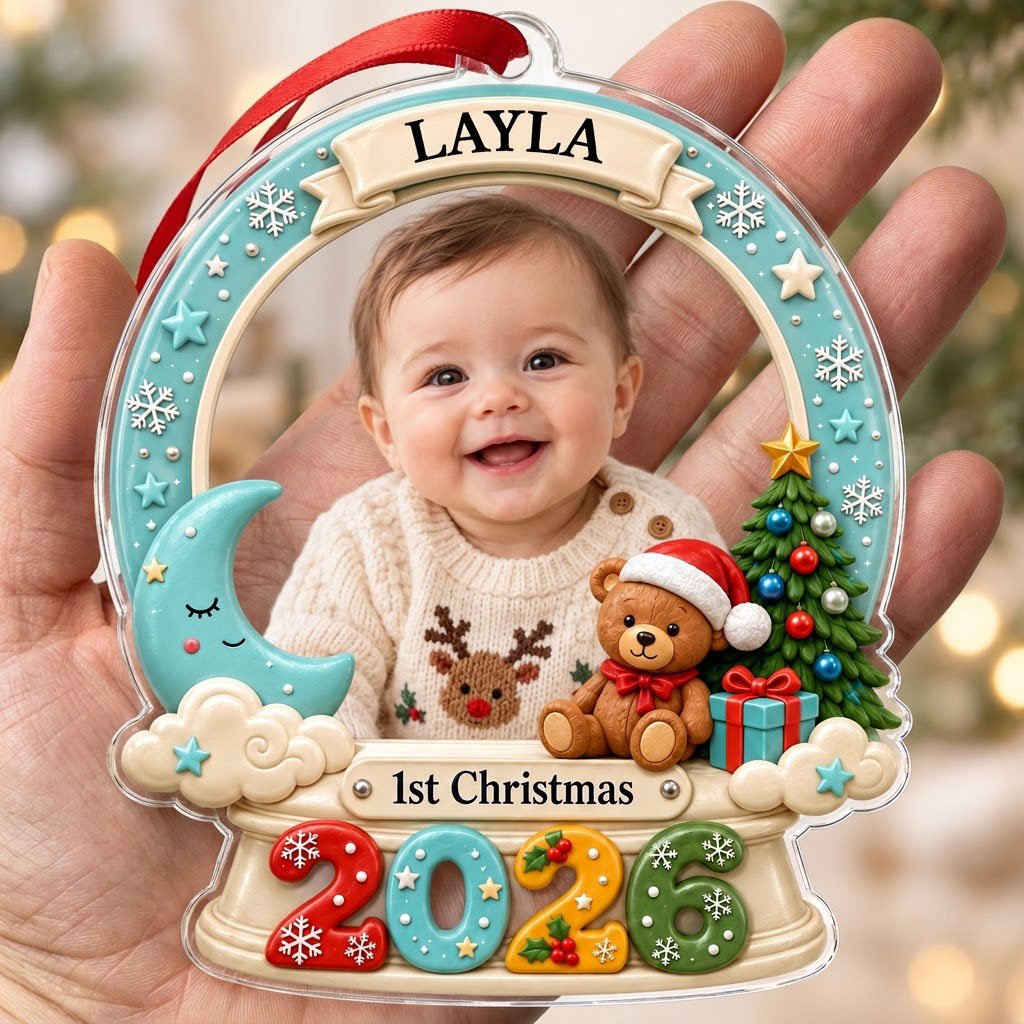 Acrylic snow-globe ornament with baby photo, "1st Christmas", teddy bear, moon, clouds, and big 2026 at the base.