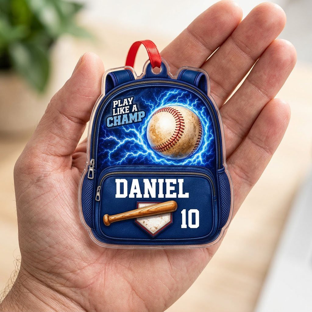 Backpack-shaped acrylic ornament with a baseball, blue lightning, a bat on home plate, and PLAY LIKE A CHAMP text.
