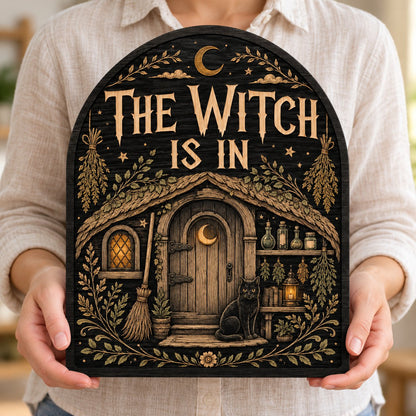 Arch wood sign with "THE WITCH IS IN", witch cottage, black cat, broom, herbs and lantern details.