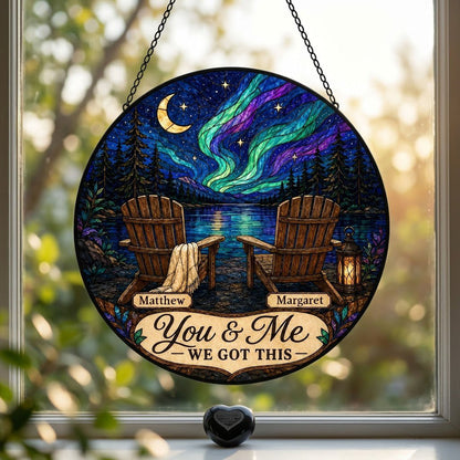 Round stained-glass style suncatcher with aurora, crescent moon, pine trees, lake, two chairs and a lantern.