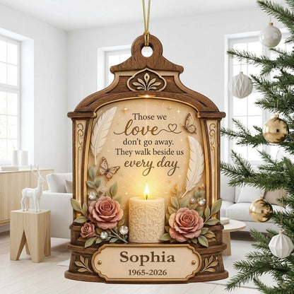 Arched wood-look ornament with lit white candle, two pink roses, butterflies, feathers, and a memorial quote.
