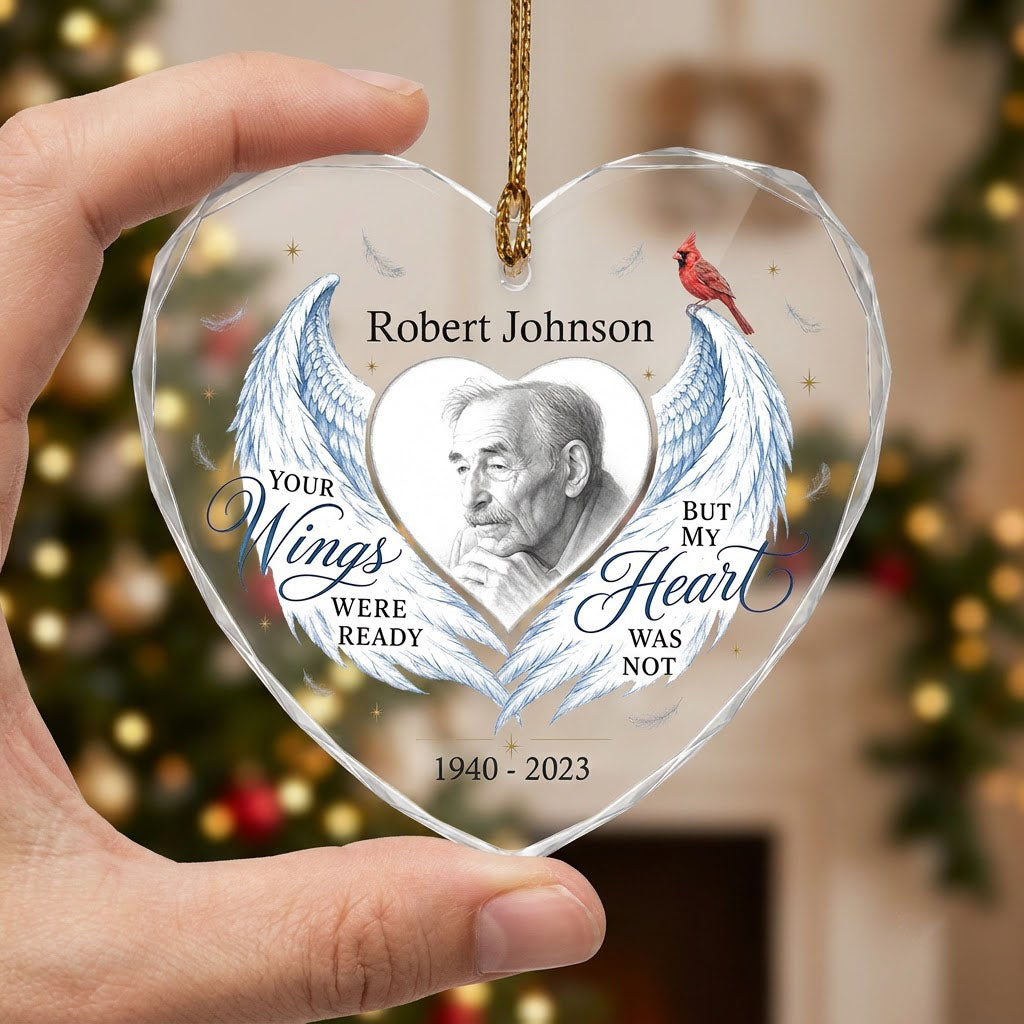 Heart-shaped glass ornament with blue angel wings, red cardinal, and a memorial quote with name and years.