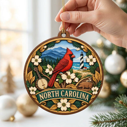Round ornament with red cardinal, dogwood flowers, mountains, lighthouse, banjo, and 'NORTH CAROLINA' text.