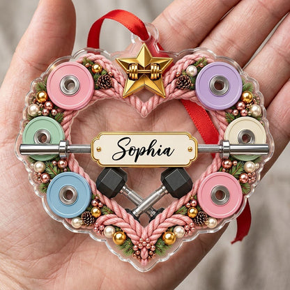 Clear acrylic heart ornament with pink rope wreath, pastel plates, barbell, crossed dumbbells, and a name plaque.