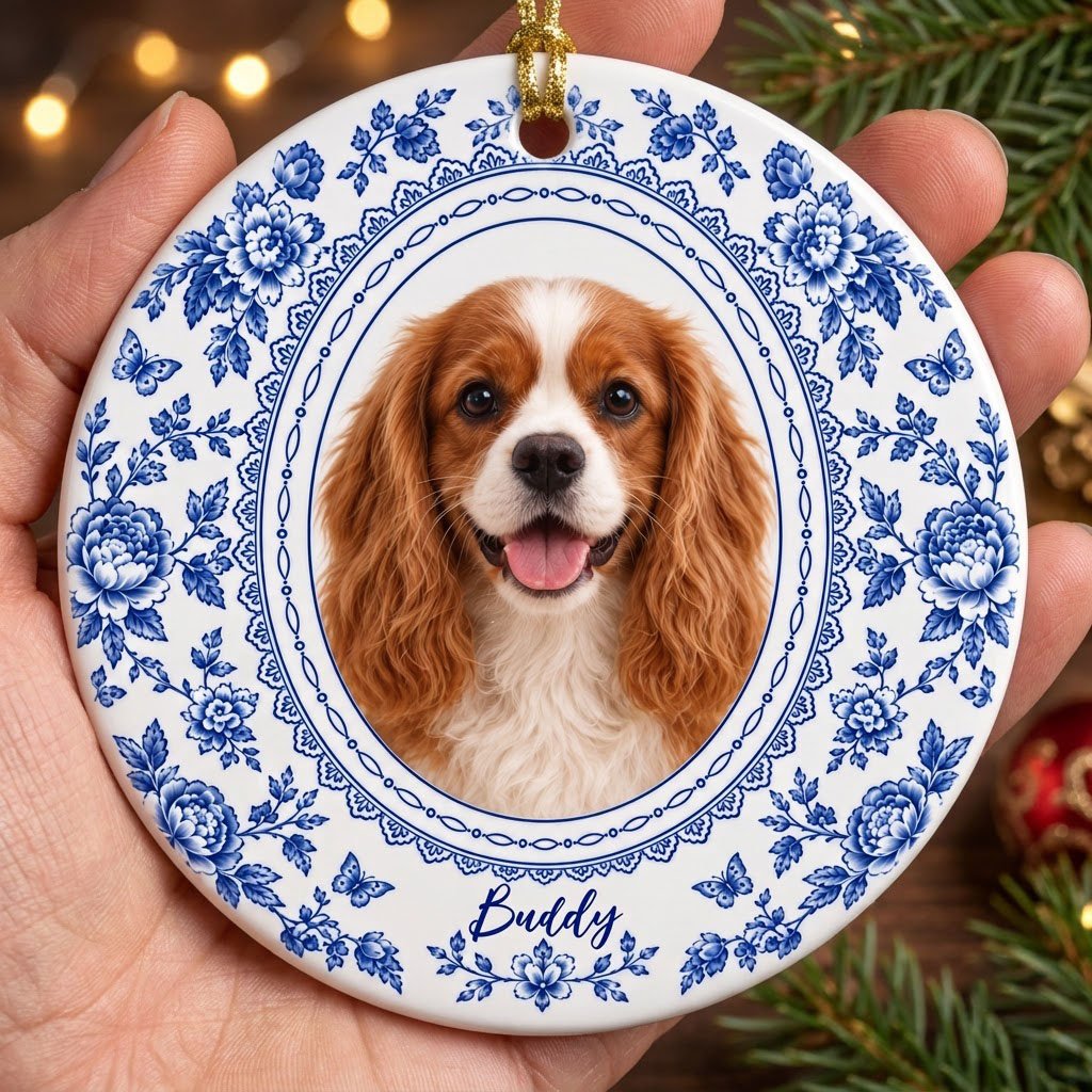 Round white ceramic ornament with blue Delft floral and butterfly pattern around an oval dog photo and name.