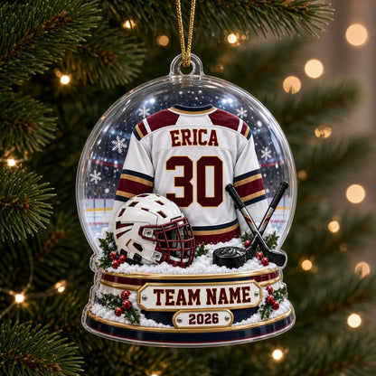 Acrylic snow globe ornament with hockey jersey, helmet, crossed sticks, puck, snowflakes and holly accents.
