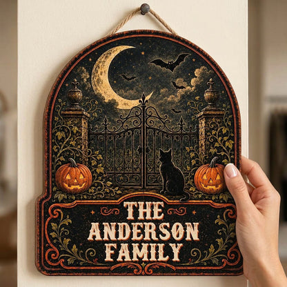Arched wooden sign with crescent moon, bats, wrought-iron gate, black cat and jack-o'-lanterns with family name.