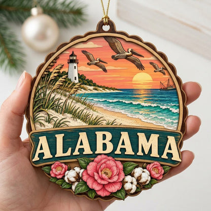 Scalloped wood ornament of an Alabama coastal scene with lighthouse, pelicans, camellias, cotton, and teal banner