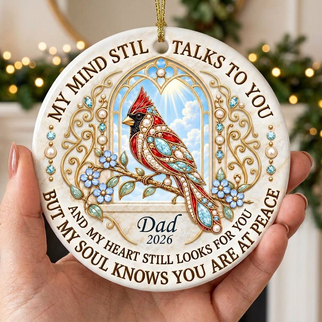 Round ceramic ornament with a red cardinal by a gold arched window, blue flowers, pearls, and a faux marble border.