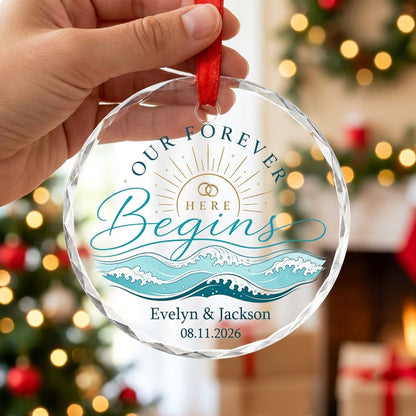 Round glass ornament with gold sun, interlocking rings, teal ocean waves, and 'OUR FOREVER HERE Begins' text.