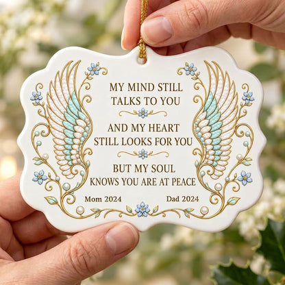 Medallion ceramic ornament with gold-outlined angel wings, blue forget-me-nots, and a memorial quote with name and year.