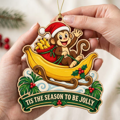 Custom-cut wood ornament with monkey in Santa hat riding a banana sleigh, banner reads TIS THE SEASON TO BE JOLLY.
