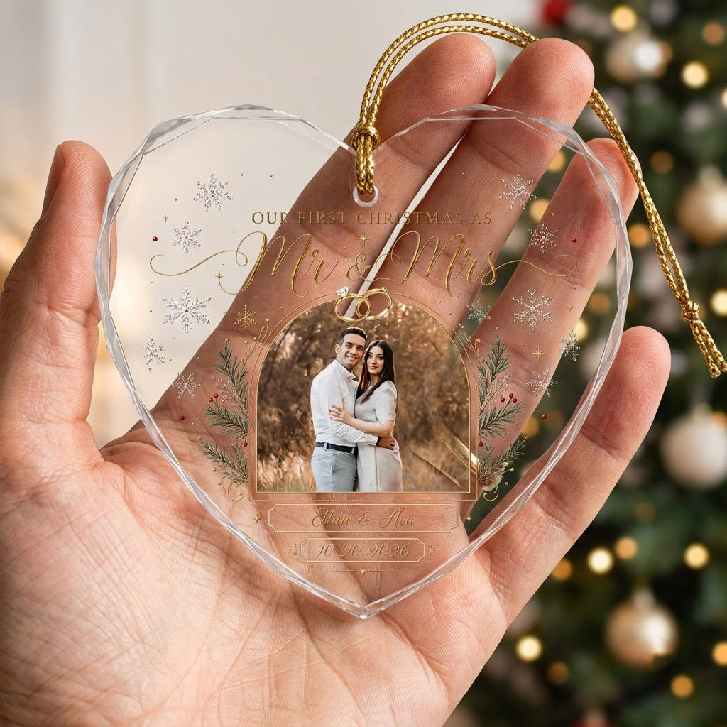 Heart-shaped glass ornament with photo, gold wedding rings, pine branches, snowflakes, and Mr & Mrs text.
