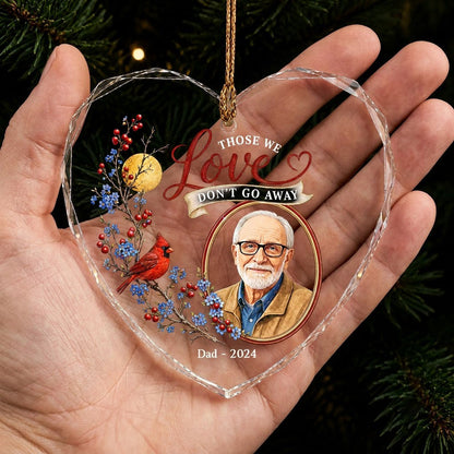 Heart-shaped glass ornament with a red cardinal, golden moon, photo frame and the quote 'THOSE WE Love DON'T GO AWAY'.